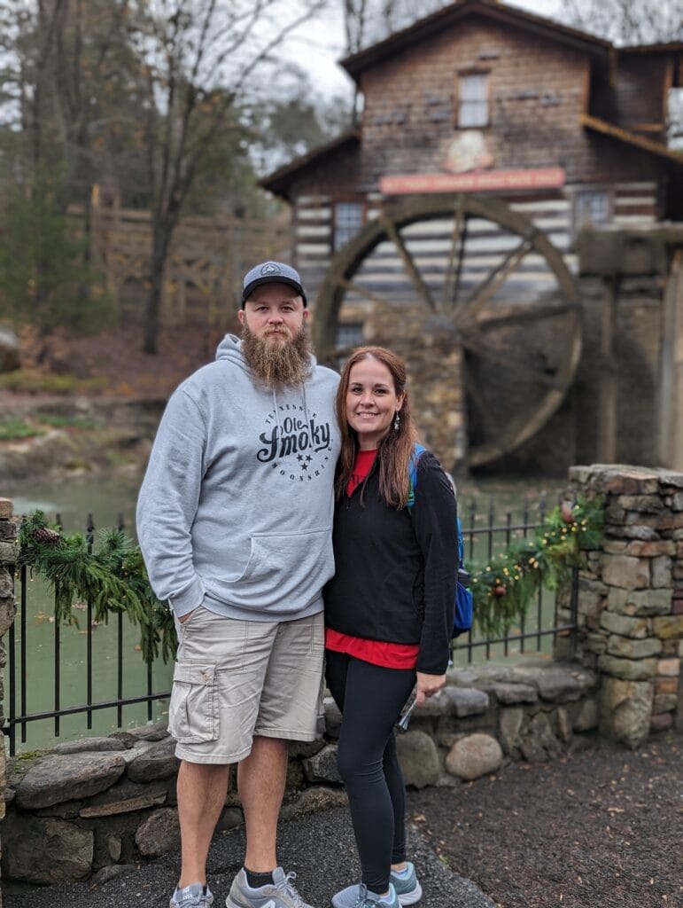 Couple standing in front of grist mill water wheel in Dollywood