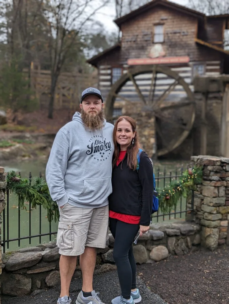 Couple standing in front of grist mill water wheel in Dollywood