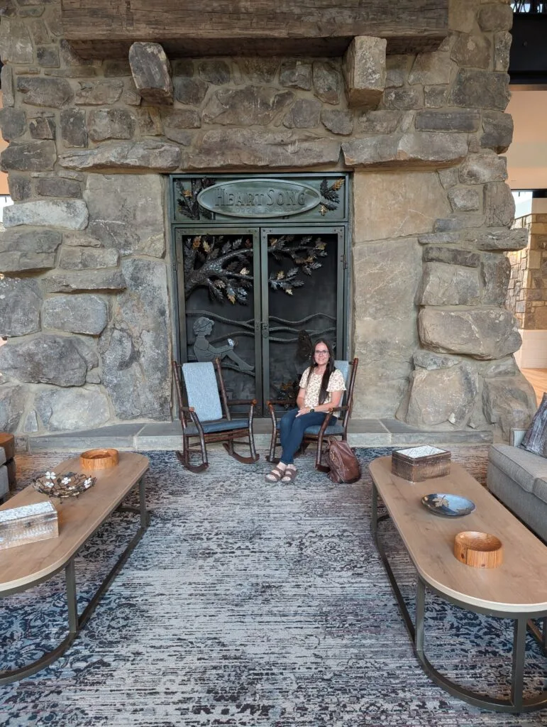 Dollywood's HeartSong Lodge & Resort: Serenity and Perks Galore 21 Lindsay Harvey in front of fireplace at HeartSong Lodge and Resort