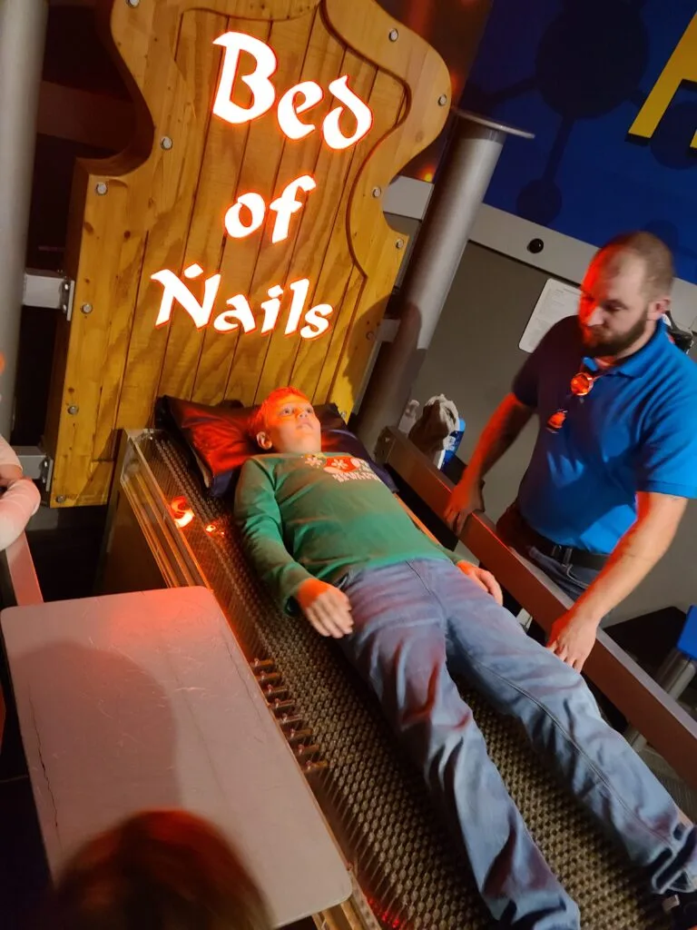 Child laying on bed of nails inside of Wonderworks in Pigeon Forge, TN Photo Credit: Lindsay Harvey-Simply Touring