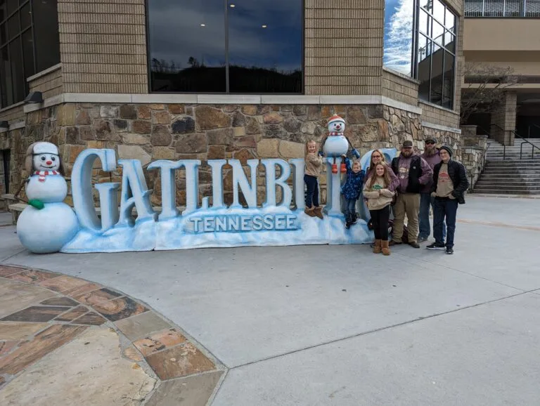 The Ultimate Holiday Plan for Your Smoky Mountain Christmas Adventure 11 Family with the Gatlinburg TN sign Photo Credit: Lindsay Harvey-Simply Touring